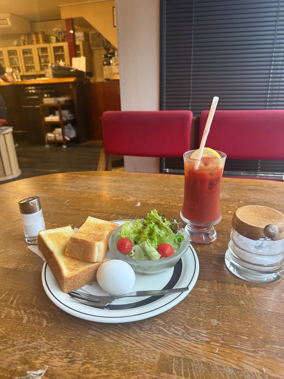 トースト、サラダ、ゆで卵に赤い飲み物が付いたモーニング