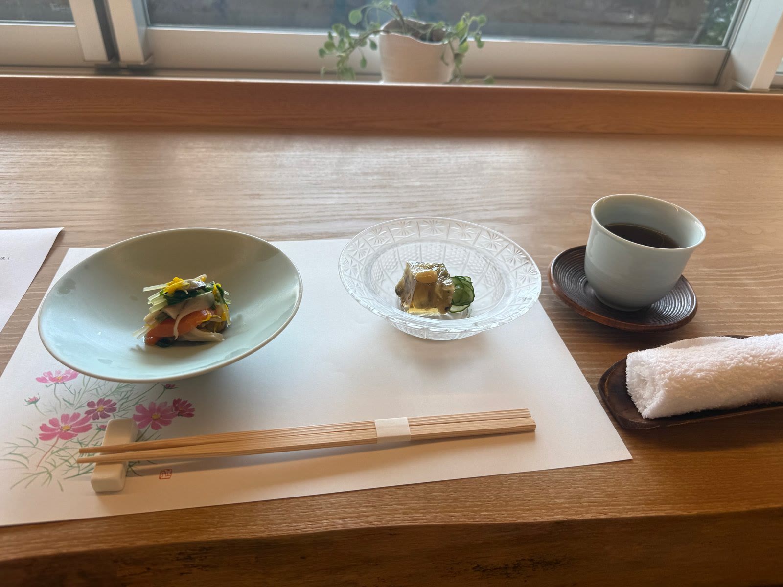 窓辺の席に並んだ前菜二品とお茶、おしぼり