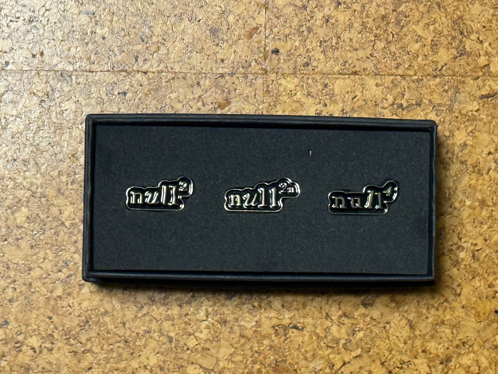 黒い箱に並んで収まった3つのnull²のピンバッジ